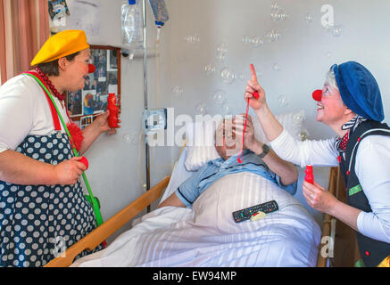 Schwerin, Germania. 05 Giugno, 2015. Ospedale clown "bene" (Ines Vowinkel, R) e 'Kiki' (Kerstin Daum) sorpresa Guenther Piehl con bolle di sapone durante un tour attraverso i reparti di assistenza infermieristica del 'Augustenstift' nursing home in Schwerin, Germania, 05 giugno 2015. I clown hanno visitato i pazienti dementi e le persone che richiedono una cura una volta al mese per gli ultimi due anni. Foto: Jens Buettner/dpa/Alamy Live News Foto Stock