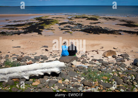 Coppia Matura seduto sulla spiaggia di Embleton Northumberland guardando al mare Foto Stock