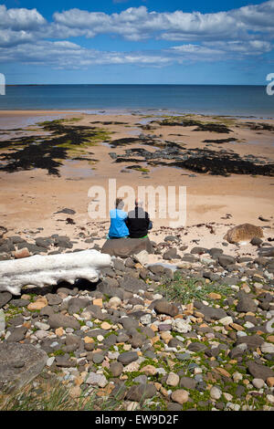 Coppia Matura seduto sulla spiaggia di Embleton Northumberland guardando al mare Foto Stock