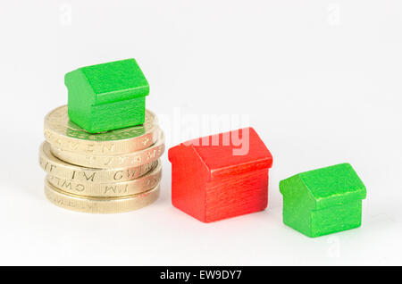 Pila di British pound monete con il rosso e il verde le case in legno Foto Stock