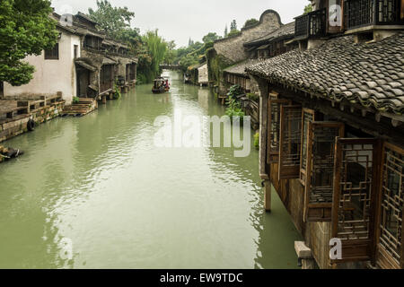 Ponte di pietra e gondola sul canale che corre tra le tradizionali case cinesi nella storica e panoramica città d'acqua di Wuzhen, Cina Foto Stock