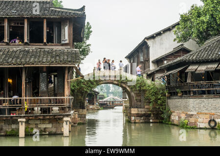 Ponte in pietra ad arco sul canale tra due ristoranti tradizionali cinesi nella storica e panoramica città d'acqua di Wuzhen, Cina Foto Stock