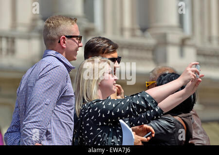 Londra, Inghilterra, Regno Unito. Tre persone in Piccadilly Circus prendendo un gruppo selfie Foto Stock