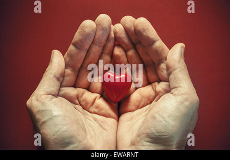 Due maschio mani rosso cuore di legno, composizione concettuale sull'amore. Foto Stock