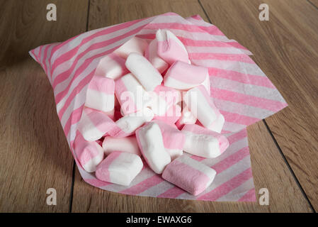 Marshmallows bianco e rosa in sacchi di carta su una superficie in legno Foto Stock