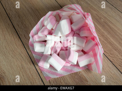 Marshmallows bianco e rosa in sacchi di carta su una superficie in legno Foto Stock