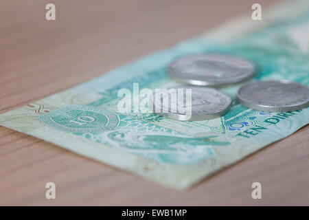Dieci Dirham nota e monete, moneta degli Emirati Arabi Uniti su un tavolo di legno Foto Stock