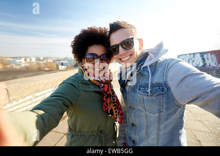 Felice coppia adolescente tenendo selfie sulla strada di città Foto Stock