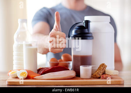 Uomo con cibo di proteina che mostra pollice in alto Foto Stock