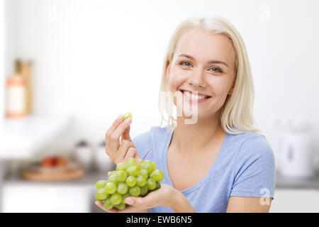 Donna felice di mangiare uva in cucina Foto Stock