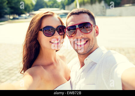 Coppia sorridente indossando occhiali da sole rendendo selfie Foto Stock