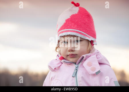 Carino bionda caucasica Baby girl in rosa hat arrabbiato acciglia, outdoor closeup ritratto Foto Stock