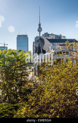 Prenzlauer Allee con la torre della TV, Park Inn e facciata di edificio con la street art, Berlino, Germania Foto Stock