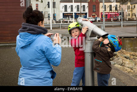 Irlanda, Co Wexford e la cittadina di Wexford, donna di scattare una foto di figli giocare con il telescopio di banchina Foto Stock