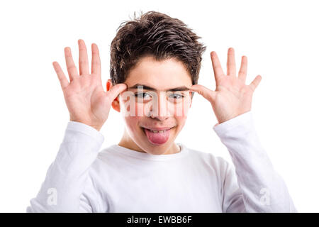 Divertenti ragazzo caucasico con acne-incline pelle in un bianco a maniche lunghe t-shirt smorfie sorrisi e agitando le mani accanto al viso Foto Stock