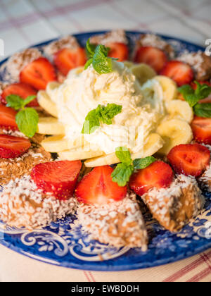 Dolce al cioccolato con banana, fragola e menta sotto la panna montata Foto Stock