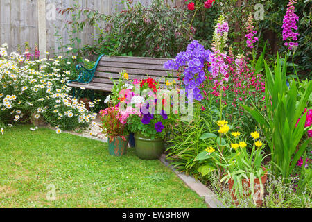 Garden Cottage con panca di legno e fiori in contenitori. Foto Stock