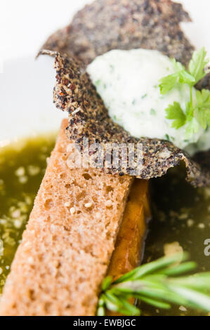 Salate toast alla francese 3.0, riempito con parmigiano Royal, tapenade a molla, un cetriolo mouse e un nero di quinoa croccante, con spinaci e ortica brodo, servita à la Nage, sul tram Hoftrammm ristorante, Den Haag, Paesi Bassi. Foto Stock