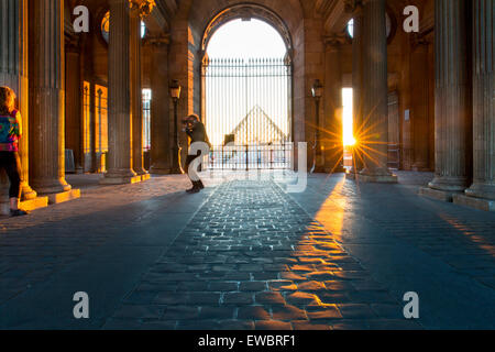 Fotografo e modello a cancelli di entrata al Musee du Louvre al tramonto, Parigi, Francia Foto Stock