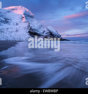 Alba invernale sulla neve coperto vette che si eleva al di sopra Bunes beach, Moskenesøy, Isole Lofoten in Norvegia Foto Stock