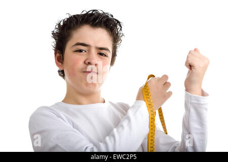 Liscia caucasico-pelato boy in bianco a maniche lunghe t-shirt è perplesso durante la misurazione il muscolo dei suoi bracci sinistro con metro giallo tape Foto Stock