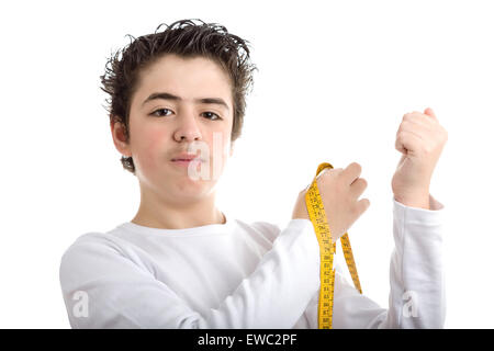 Liscia caucasico-pelato boy in bianco a maniche lunghe t-shirt è perplesso durante la misurazione il muscolo dei suoi bracci sinistro con metro giallo tape Foto Stock