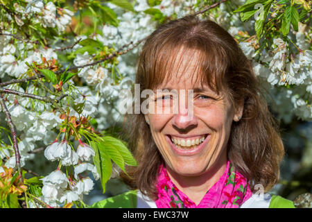 Testa di soggetti di razza caucasica donna di mezza età tra i fiori bianchi in primavera Foto Stock
