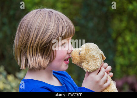 Giovane ragazza caucasica abbracciando cane di peluche contro il suo naso Foto Stock