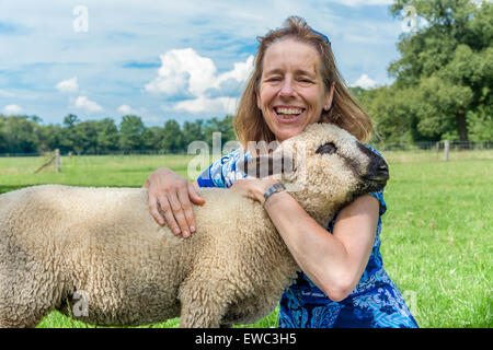 Donna europea che abbraccia e abbracciando le pecore in Prato Foto Stock