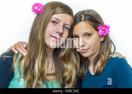 Due adolescenti caucasici sorelle indossando le rose rosa che abbraccia ogni altro Foto Stock