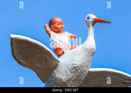 Baby doll seduta su di cicogna con cielo blu Foto Stock