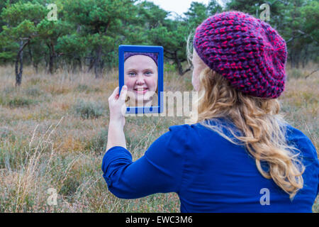 Dutch ragazza adolescente holding specchio nella natura e guardando se stessa Foto Stock