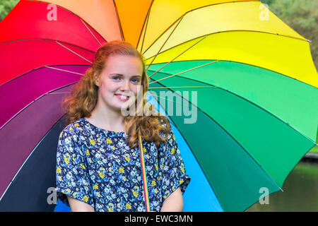 Caucasian ragazza adolescente all'aperto sotto ombrellone con vari colori Foto Stock