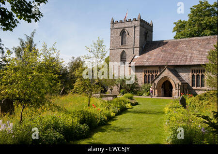 La chiesa di Santa Maria, Kettlewell, Yorkshire Dales, Inghilterra, Regno Unito. 1 lady in piedi dal portico, bellissimo giardino con fiori di prato, estate sole e cielo blu. Foto Stock