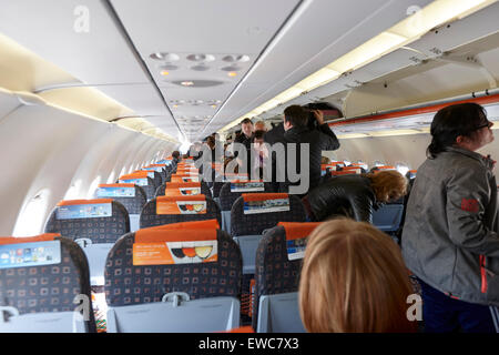 Passeggeri posto per i bagagli a mano in scompartimenti sopraelevati sul volo Easyjet subisca l'Aeroporto Internazionale di Belfast Regno Unito Foto Stock