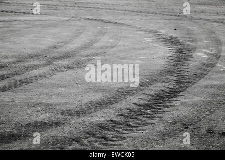 Abstract di trasporto con sfondo nero di tornitura tracce di pneumatici su asfalto scuro pavimentazione stradale Foto Stock