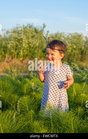 Funny bambina come indiano con le maracas e piuma Foto Stock