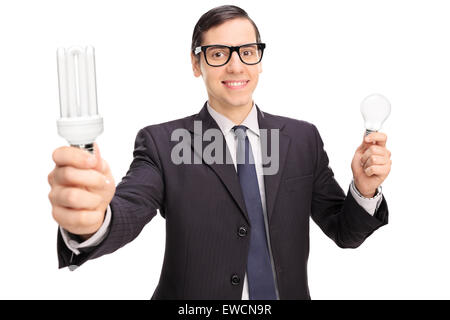 Yong uomo in un abito nero di trattenimento di un risparmio energetico lampadine di una mano e di una normale lampadina in altri Foto Stock