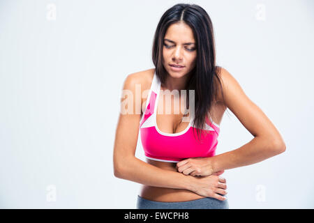 Ritratto di una donna fitness con dolore di stomaco su sfondo grigio Foto Stock