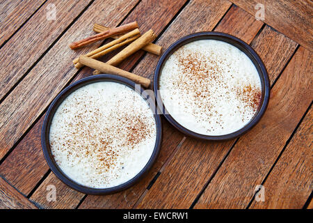 Argilla blu casseruola con budino di riso e bastoncini di cannella Foto Stock