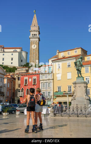 I turisti sulle lame a rullo a Tartini piazza con la statua di Giuseppe Tartini con la chiesa di San Giorgio dietro. Pirano. Foto Stock