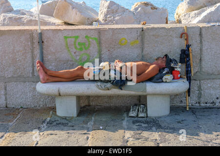 Un giovane uomo addormentato su un banco di calcestruzzo. Pirano. La Slovenia, Foto Stock