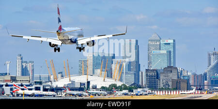 Volo British Airways in atterraggio a London City Airport (Newham) con l'O2 Arena e Canary Wharf (Tower Hamlets) skyline al di là Foto Stock