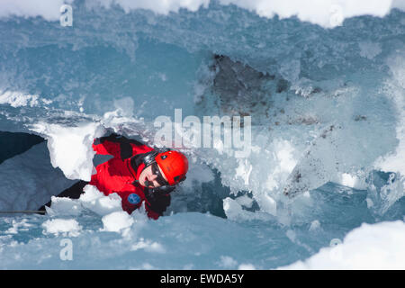 Un soccorso alpino paramedico è lontano in giù in un crepaccio sul ghiacciaio cercando fino alla superficie. In inverno il soccorso di montagna Foto Stock