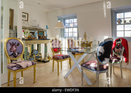 Sala da pranzo dorato sedie tappezzate in Cory di stampe Visitorian attorno al ripiano in vetro tavolo da pranzo Foto Stock