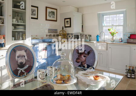 Sedie da pranzo rivestita in Cory di stampe Visitorian attorno al ripiano in vetro tavolo da pranzo in cucina con cassettiera bianco e aga Foto Stock