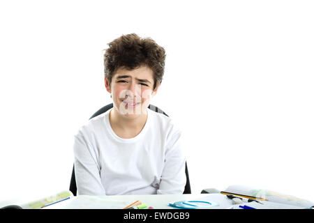 Carino liscia caucasico-pelato boy tristemente seduto di fronte a compiti che indossa una bianca maniche lunghe t-shirt Foto Stock