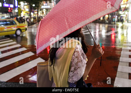 Una giovane donna con ombrello in caso di pioggia in Shibuya di notte a Tokyo in Giappone Foto Stock