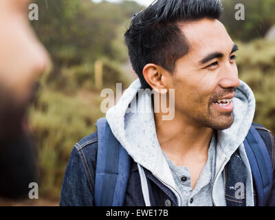 Due uomini, uno sorridente indossando un top con cappuccio Foto Stock
