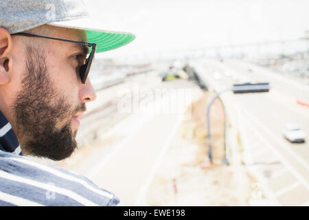 Close up di un barbuto giovane uomo che indossa gli occhiali da sole e un cappello da baseball Foto Stock